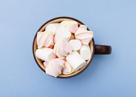Sweet marshmallow in cup, candy on blue background, top view flat lay. Isolated minimal concept above decoration, view white marshmallow, food backgroundの写真素材