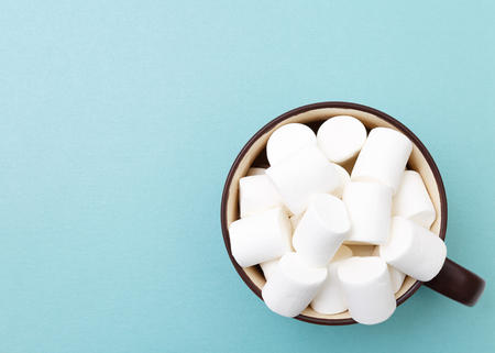 Sweet marshmallow in cup, candy on blue background, top view flat lay. Isolated minimal concept above decoration, view white marshmallow, food backgroundの写真素材