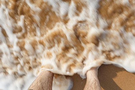 ocean waves beating against legs on the beachの写真素材