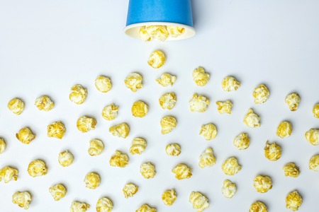 Popcorn spill concept. Isolated white background. Delicious sweet popcorn for watching new movies in...