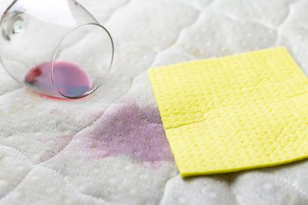 Sponge cleaning wine stain. Dropped wineglass. Spilled wine on white couch. Routine housework.の写真素材