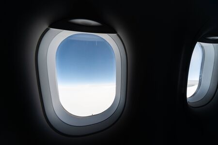 Airplane window view to cloudy sky and earth. Beautiful landscape from aircraft cabin. Flying without fear of flying, incidents and turbulence.の写真素材