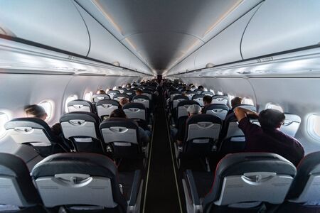 Airplane cabin seats with passengers. Economy class of new cheapest low-cost airlines without delay or cancellation of flight. Travel trip to another country.の写真素材