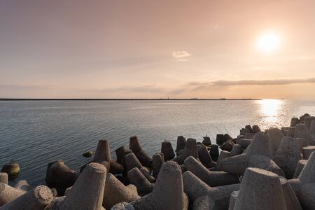 Tetrapod breakwaters in sea water. Beautiful sunset seascape with concrete tetrapodes for protect coastal structures from storm sea waves, effects of weather and longshore driftの写真素材