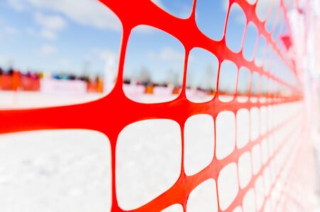 Safety outdoor slope track fence, winter background. Fence to protect spectators at sports events, or to indicate course at extreme sports - dog sledding, snowboarding or skiingの写真素材