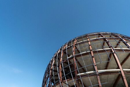 Unfinished sphere shape building, copy space. Construction of futuristic shopping mall or museum. Building constructed of concrete and reinforcement.の写真素材