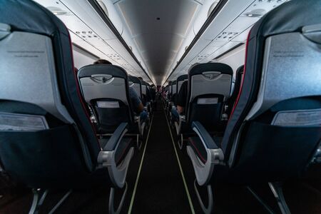 Airplane cabin seats with passengers. Economy class of new cheapest low-cost airlines without delay or cancellation of flight. Travel trip to another country.の写真素材