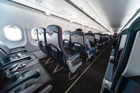Airplane cabin seats with passengers. Economy class of new cheapest low-cost airlines. Travel trip...