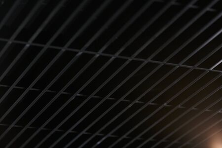 Office grille ceiling. Modern black metal grille ceiling, suspended covering. Abstract design texture.の写真素材