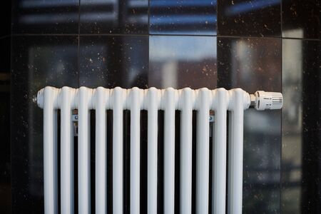 Heating radiator in office, close up. White heat exchangers. Iron aluminium steam radiator. Pipe pattern.の写真素材