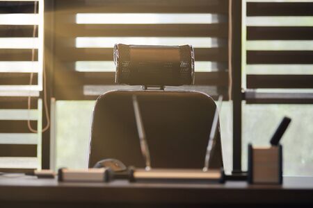 Business office workplace. Sunlight at work place for chief, boss or other employees. Table and comfortable chair. Light through the half open blindsの写真素材