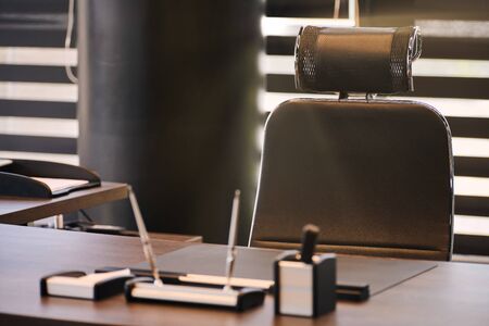Business office workplace. Sunlight at work place for chief, boss or other employees. Table and comfortable chair. Light through the half open blindsの写真素材