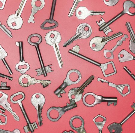 Keys set on pink background. Door lock keys and safes for property security and house protection. Different antique and new types of keys.の写真素材