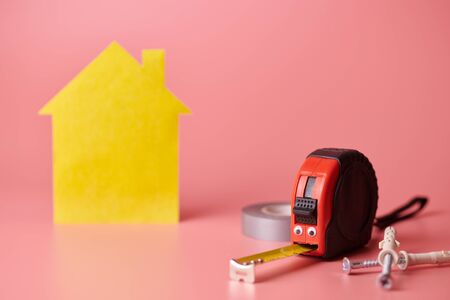 House renovation funny concept. Metal tape measure and other repair items. Home repair and...