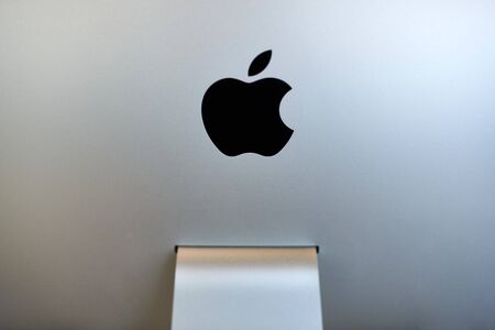 Apple iMac modern computer. Apple logo on monitor, workplace in office. New hardware equipment -...