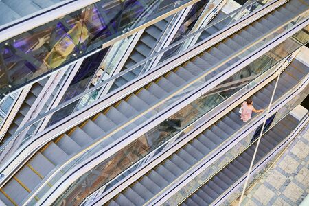 Crisscross escalators in shopping center. Empty escalators stairs up and down in office building, shopping mall or subway station.の写真素材