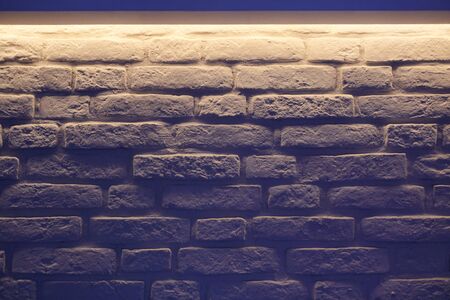 Brick wall indigo lighting. White wall blue glow in modern vintage loft interior. Unusual room...