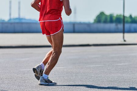 Running old man. Old man jogging in sportswear on city road. Healthy lifestyle, fitness sport hobby. Street workout, sprinting outdoorの写真素材