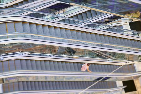 Crisscross escalators in shopping center. Empty escalators stairs up and down in office building,...