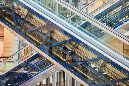 Crisscross escalators in shopping center. Empty escalators stairs up and down in office building,...