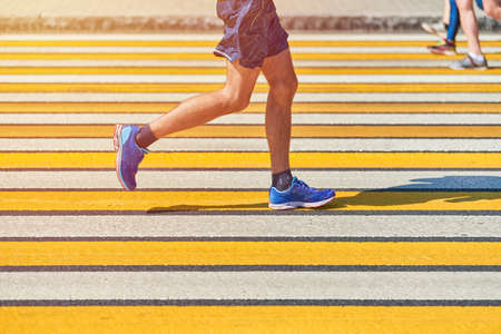 Man running crosswalk, copy space. Athletic man jogging in sportswear on city road. Healthy lifestyle, fitness sport hobby. Traffic violation. Street workout, sprinting outdoorの写真素材