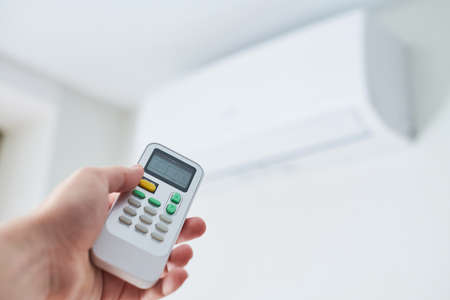 Remote control for air conditioner in hand. Room condition remote control. Air temperature switch...
