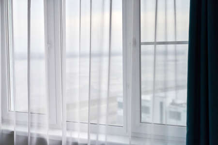 Windows with curtains in rental apartment. Cityscape view. Light window in the roomの写真素材