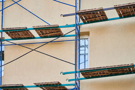 Scaffolding on construction site. Incomplete building and decoration with scaffolds. Work in...