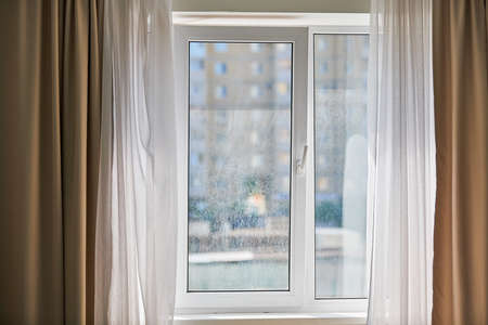 Dirty window in apartment. Unwashed dusty glass, city street view background. Unclean double glazed windowの写真素材