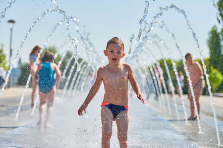 Cute boy playing in fountain. Little boy playing with waterspouts. Exciting and happy childhood. Impressive summer water funのeditorial素材
