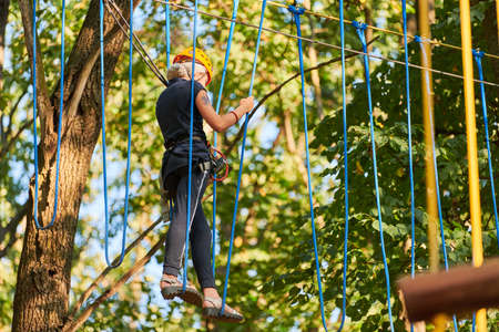 Girl in high ropes experience adventure tree park. Rope road course in trees. Climbing adventure...
