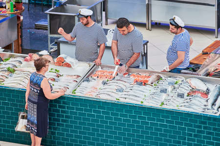 Voronezh, Russia, 23.08.2019 - Fish sellers in local market. Fishmongers discuss fish discount with customer. Various freshly caught seafood on market counter.のeditorial素材