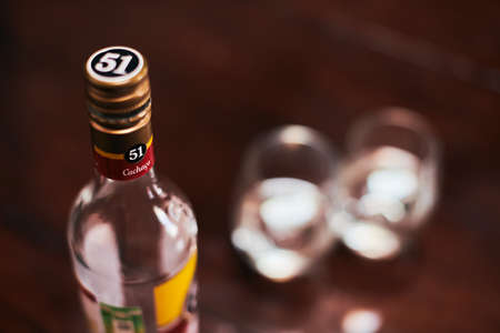 Moscow - 11/23/2019 - Cachaca 51 bottle with two glasses. Brazilian rum. Exotic Brazil strong alcohol drink rom fermented sugarcane juice. Loft apartment background.のeditorial素材