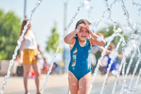 Voronezh, Russia - 24.08.2019 - Cute baby playing in fountain. Little girl playing with waterspouts. Exciting and happy childhood. Impressive summer water funのeditorial素材
