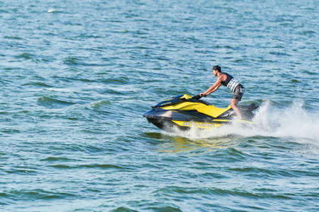 Voronezh, Russia - 23.08.2019 - Man on water scooter. Splashes and drops around. Summer vacation on personal watercraft in tropical sea. Young guy sea riding hobby. PWC sport activityのeditorial素材
