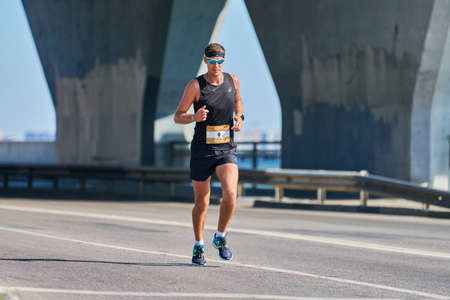 Voronezh, Russia - 08.24.2019 - Young man runs along road. Runners marathon and championship...