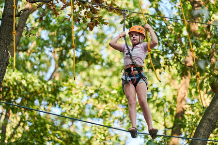 Voronezh, Russia - 24.08.2019 - Girl in high ropes experience adventure tree park. Rope road course in trees. Climbing adventure rope park. Wood bridge and high wire activity.のeditorial素材