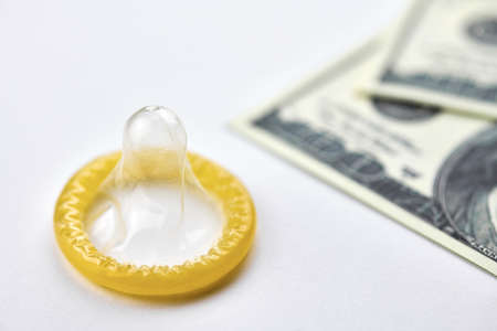 Condom on dollars bills. Prostitution concept. US dollar money on table with contraceptive. Pay for sex per night. Harlotry and whoredom.の写真素材