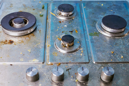 Dirty gas stove top with food leftovers. Unclean steel kitchen cooktop with greasy spots. Spring-cleaning, remove kitchen old fat stains, fry spots, oil splatters and burned-on bitsの写真素材