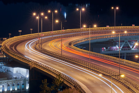 Highway at night lights. Fast car light path, trails and streaks on interchange bridge road. Night...