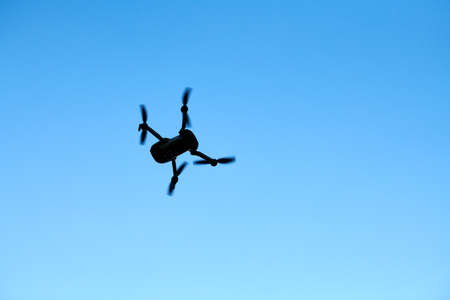 Quadcopter drone in sky. Small drone flies in sky taking video and photos. Remote control air delivery and spy.の写真素材