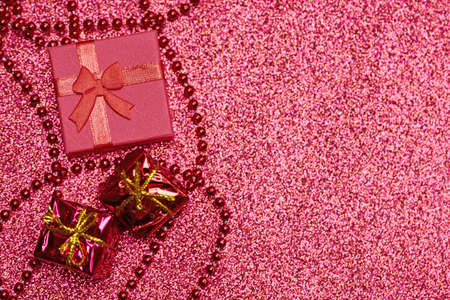 Red gift box on festive glitter. Little closed box with bow and gift for anniversary or wedding. Surprise giftbox for loved one.の写真素材