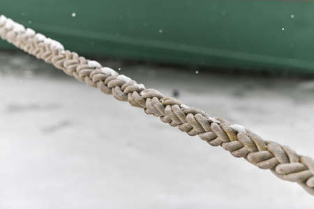 Rope tied ship on background of green ship side. Ropes hanging from fishing ship or yacht, close up.