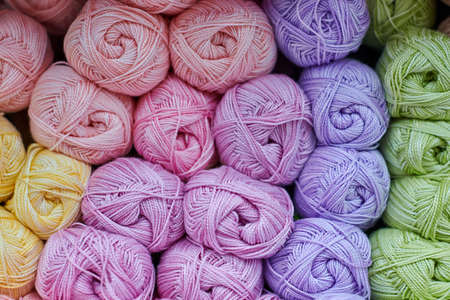 Yarns or balls of wool on shelves in store for knitting and needlework, close up. Accessories for haberdashery in fabric store shelves. Multicolored picture, background.の写真素材