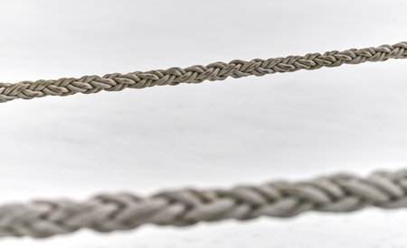 Two sail ropes hanging from fishing ship or yacht, close up. Detailed fragment of rope.