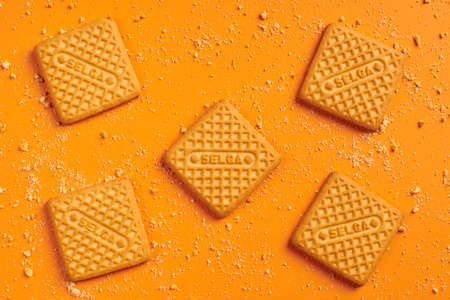 KALININGRAD, RUSSIA - 03.27.2021 - Selga biscuits. Delicious Latvian snack, SELGA square cookies on orange background, scattered crumbsのeditorial素材
