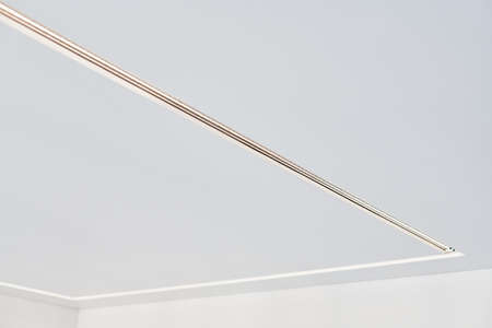 Suspended ceiling with square LED strip lamp in empty room in apartment or house. White stretch...