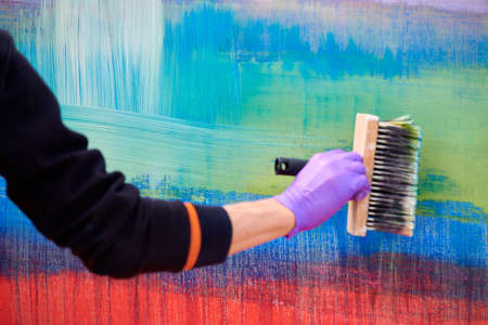 Female painter hand drawing abstract painting holding wide brush. Oil painting on colorful canvas, fragment of artwork with green, red and blue broad brushstrokes, modern art, contemporary artの写真素材