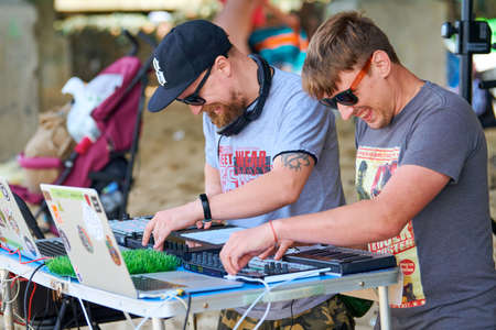 Svetlogorsk, Russia - 08.14.2021 - Disc jockeys playing music, remixing on drum machine midi controller. DJs playing beat sampler with drum pads and samples. Deejays make beats at beach party outsideのeditorial素材