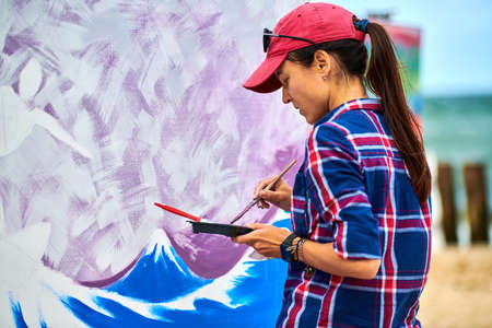 Svetlogorsk, Russia - 08.14.2021 - Female artist painting with brush on wooden canvas board at...